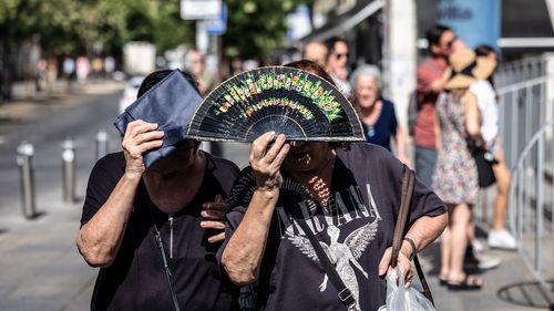 People shield themselves from the sun during high temperatures in Seville, Spain, on Thursday.