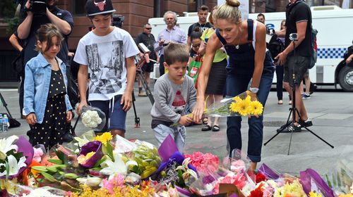 A young family lays flowers in respect at Martin Place. (Getty)