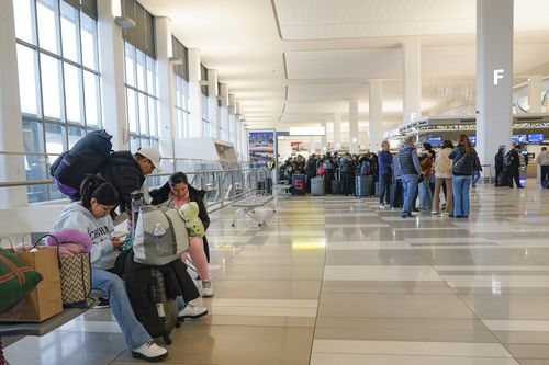 Travellers stand in the departures hall of Terminal B at LaGuardia Airport in New York, Wednesday, Jan. 11, 2023. 