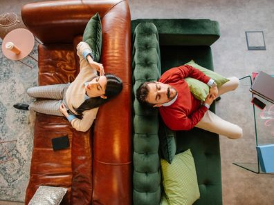 Stock image of a man and woman sitting back to back, looking upset