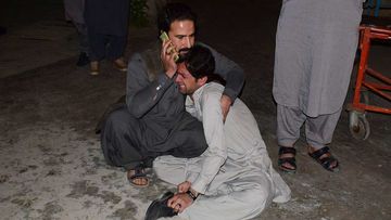 A Pakistani man comforts to another mourning over the death of his family member in a bomb blast, at a hospital in Quetta.