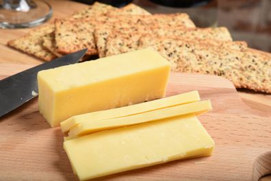 Sliced white cheddar cheese on a cutting board