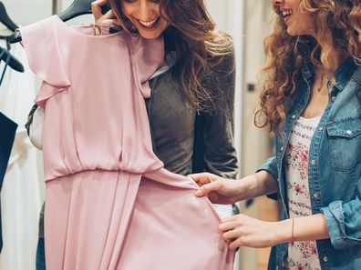 Two young women choosing dresses in a luxury fashion store