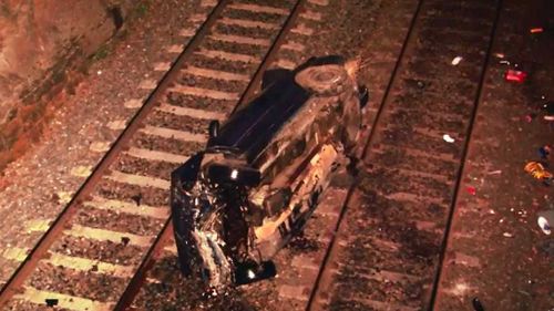 The car crashed onto train tracks below the highway. (9NEWS)