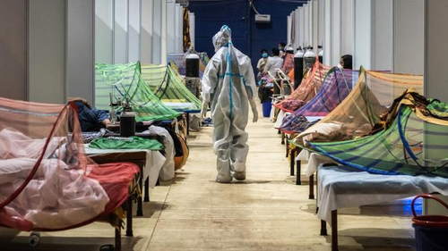 Un travailleur médical observe des patients à l'intérieur d'un service COVID-19 qui a été installé dans un stade de sport à New Delhi.