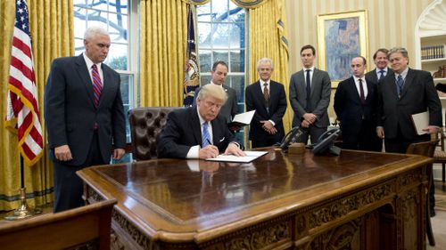 Donald Trump signs an executive order withdrawing the US from the TPP. (Getty)