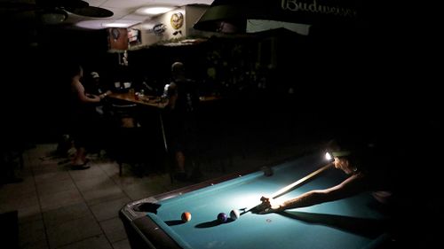 Lisa Borruso plays pool using a headlamp as the power remains out following Hurricane Irma at Gators' Crossroads in Naples. (Associated Press)