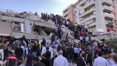 Rescue workers and local people try to reach residents trapped in the debris of a collapsed building, in Izmir, Turkey, Friday, Oct. 30, 2020, after a strong earthquake in the Aegean Sea has shaken Turkey and Greece