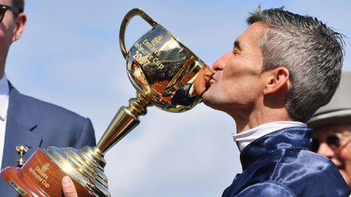 The Cup-winning jockey gives the illustrious trophy a big smooch. (AAP)