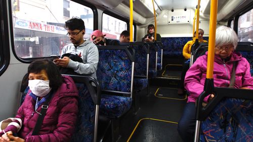 Passengers sit apart on a Sydney bus travelling down King street in Newton.