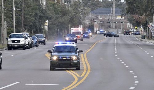 Police cars escort an ambulance after the shooting.