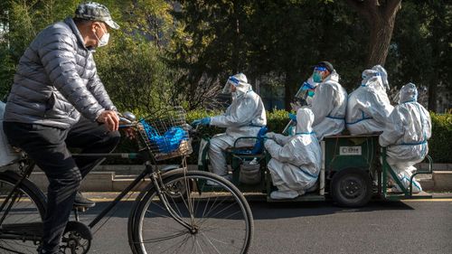 Epidemic control workers ride in a vehicle in an area of Beijing where communities are in lockdown or health monitoring to prevent the spread of COVID-19
