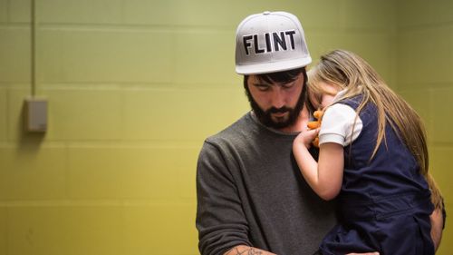 A Flint resident comforts a young girl after she gives blood to be tested for lead. (Getty)