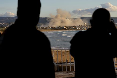 Journalists watch the smoke rising between buildings hit in Israeli airstrikes near the Palestinian refugee camp of Rashidiyeh, as it seen from Tyre city, south Lebanon, Tuesday, Nov. 26, 2024.