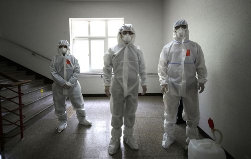 Health officials wearing protective gear prepare to spray disinfectant to help reduce the spread the new coronavirus ahead of school reopening in a cafeteria at a high school in Seoul, South Korea