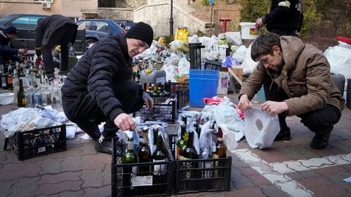 Members of civil defence prepare Molotov cocktails in a yard in Kyiv, Ukraine.
