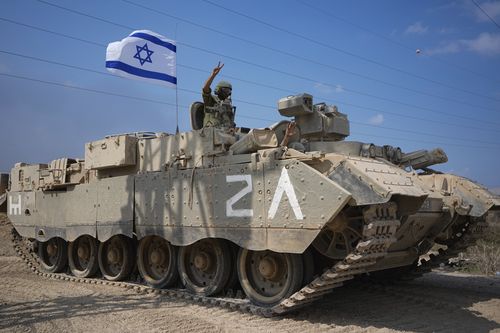 An Israeli soldier flashes a V-sign from an armoured personnel carrier (APC) as they head towards the Gaza Strip border in southern Israel, Saturday, Oct. 14, 2023. 