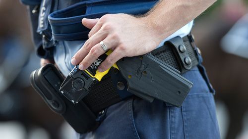 A police officer rests a hand on a taser in the Brisbane CBD. (AAP)