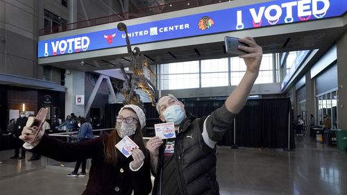 Samantha Jones and Peter Vina take selfies in the atrium of the United Center, transformed into a super voting site in Chicago. 