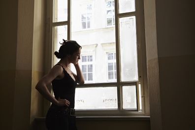 Anxious woman standing at window.