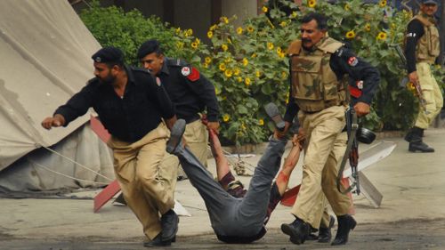Pakistani Police carry an injured man from a mosque in the area of Garhi Shahu. (Getty)