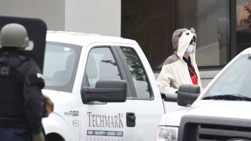 A man wearing a full animal costume and surgical mask walks out of a TV station in Baltimore. (AAP)
