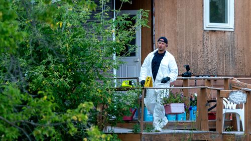 A police officer in protective gear works at the scene of a stabbing in Weldon, Saskatchewan 