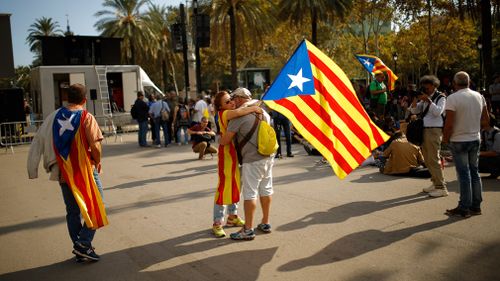 A woman holds a Catalan flag as she hugs a man during a rally in Barcelona, Spain. (AP)