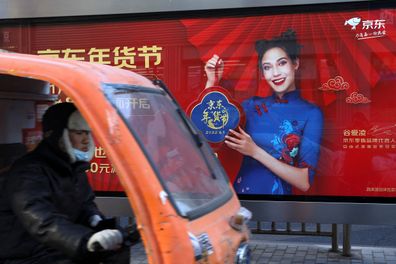 A delivery worker rides a vehicle pasts a JD.com advertisement with an image of freestyle skier Eileen Gu, at a bus stop in Beijing, China, January 11, 2022. Picture taken January 11, 2022. REUTERS/Tingshu Wang