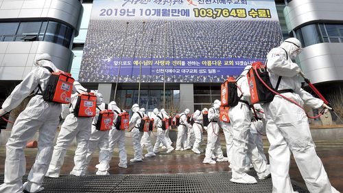 In this March 1, 2020, file photo, army soldiers wearing protective suits spray disinfectant to prevent the spread of the coronavirus in front of a branch of the Shincheonji Church of Jesus in Daegu, South Korea. As the coronavirus spreads around the world, many events that normally would draw large numbers of people are being canceled or played without fans. (Lee Moo-ryul/Newsis via AP, File)