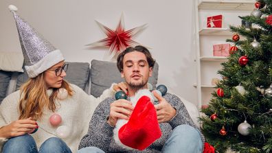 Couple sitting next to Christmas tree