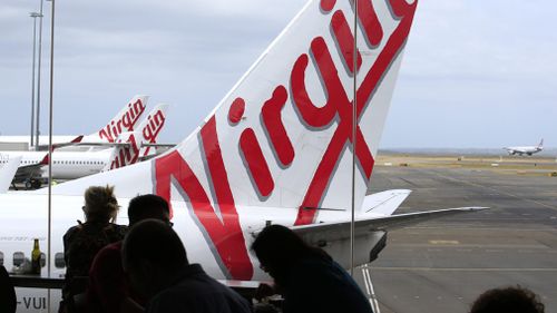 People watching a Virgin Australia aircraft on the tarmac at Melbourne Tullamarine Airport. (AAP)