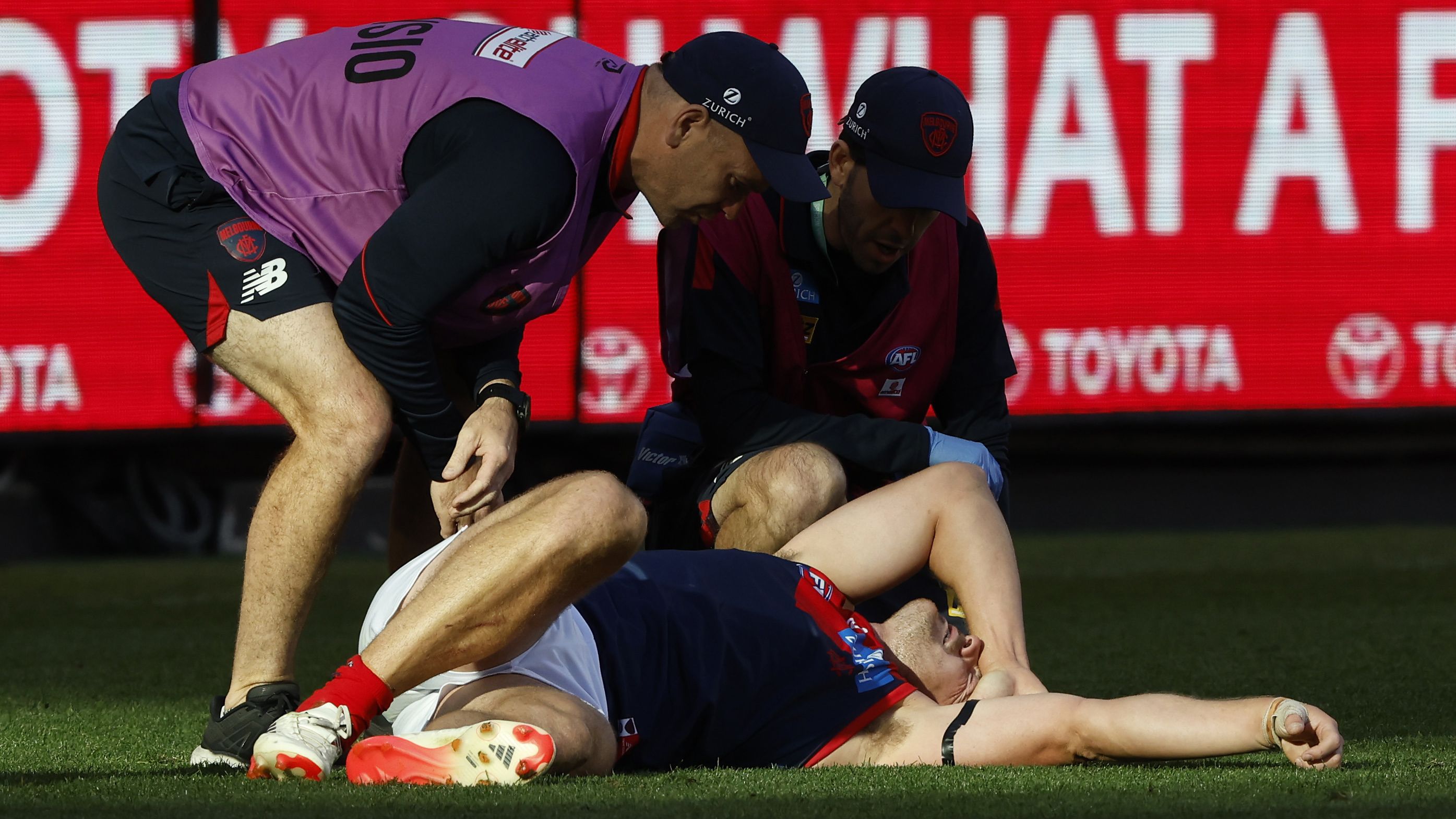 Steven May is tended to by trainers after a heavy collision during the round two AFL match between the Hawthorn Hawks and the Melbourne Demons.