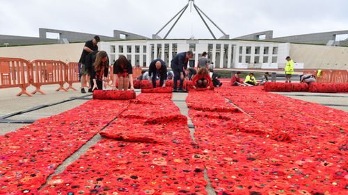 European Union ambassadors help with the installation of 270,000 poppies outside Parliament House in Canberra.