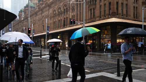 Pedestrians walk through the heavy rainfall in Sydney's CBD. 6th April 2022 Photo: Janie Barrett