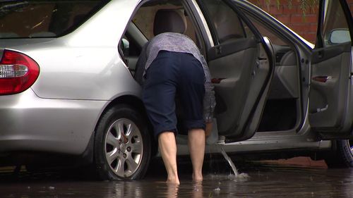 Man tries to remove water from flooded car in Marrickville.