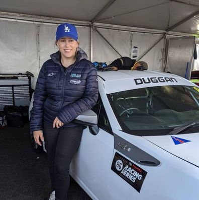 Emily Duggan race car driver next to her car