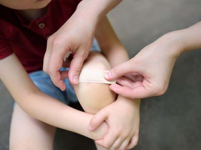 Mum putting a band-aid on her son's knee.