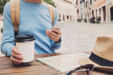 Young woman using phone in a cafe, travel concept