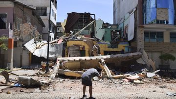 A man takes a photo of a building that collapsed after an earthquake shook Machala, Ecuador.