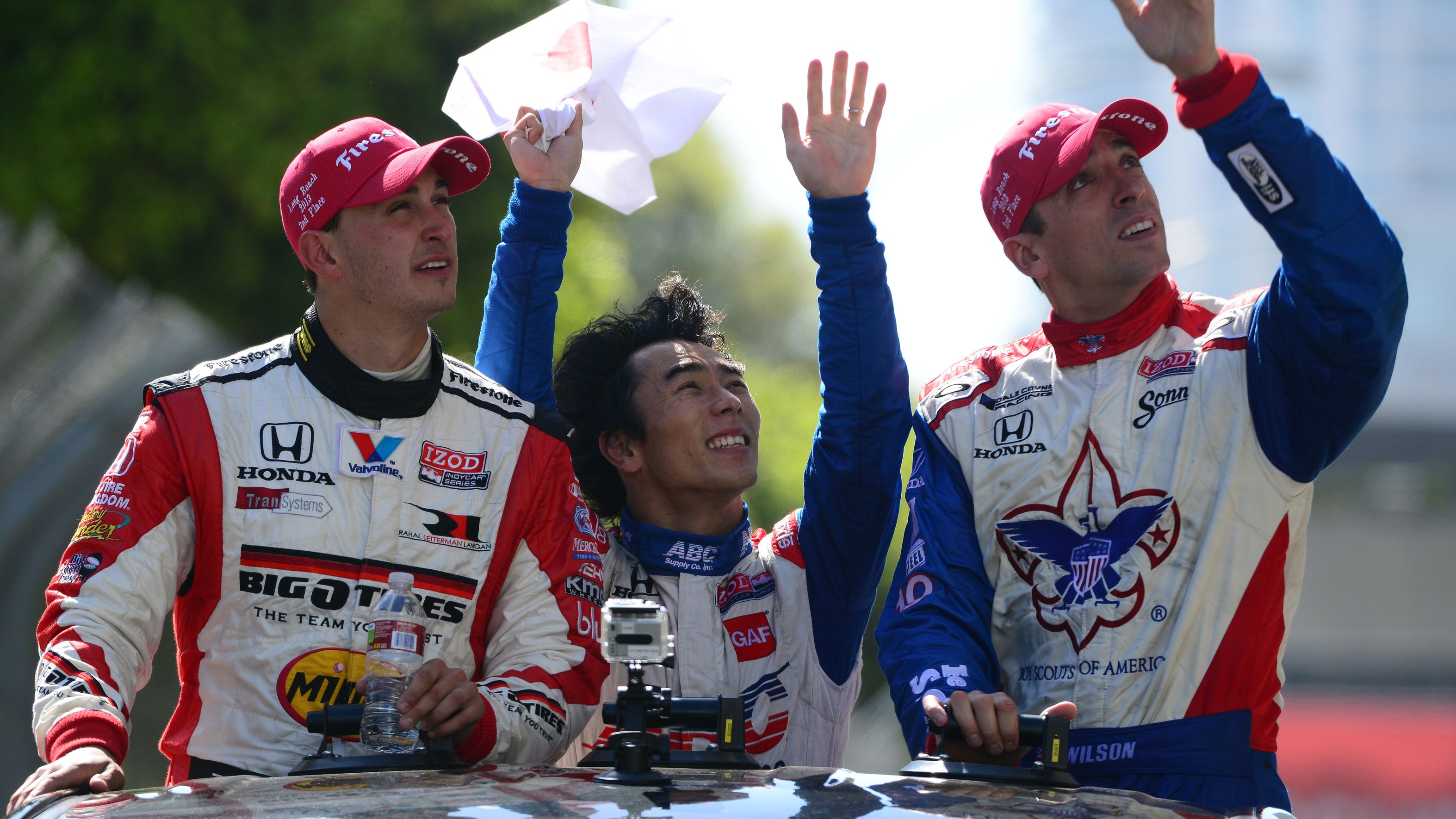 Graham Rahal (left) with Takuma Sato (centre) and Justin Wilson during a driver parade in Long Beach in 2013.