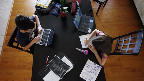 Two children do their school work at home on the dining room table as the COVID-19 coronavirus pandemic forced schools to close.