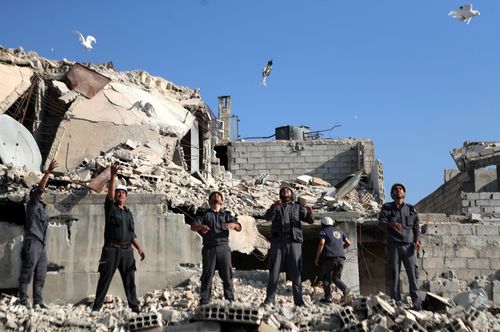 Volunteers let go of pigeons during a solidarity protest among the rubbles of destroyed houses in Zamalka, rebel-held eastern al-Ghouta in August 2017. (EPA/AAP)