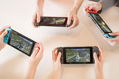 9PR: Four people playing Mario Kart  8 Deluxe on the Nintendo Switch