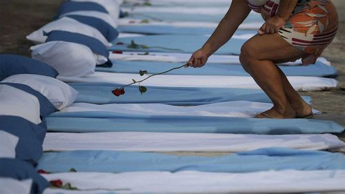 A woman is shown laying a rose on top of a mattress symbolising COVID-19 victims during a protest outside a hospital in Rio de Janeiro, Brazil.