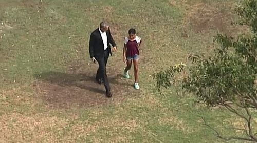 Barack Obama takes a walk with a young girl in Government House gardens. (9NEWS)