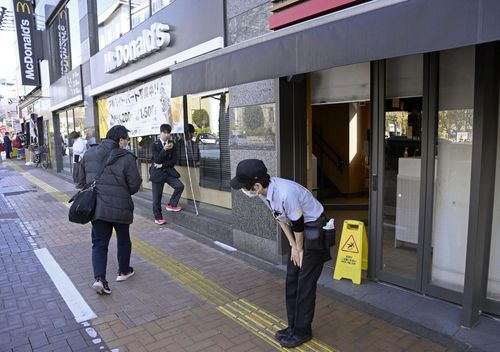 A McDonald's employee bows in front of its store amid the company's system outages in Tokyo, Friday, March 15, 2024.  