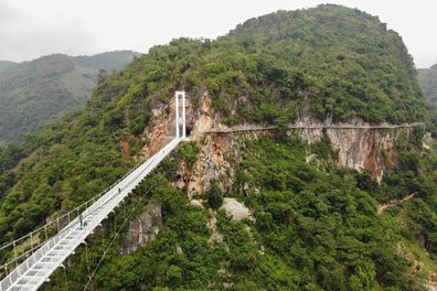 This aerial photo shows the newly constructed Bach Long glass bridge in Moc Chau district in Vietnam's Son La province on April 29, 2022. - Vietnam launched a new attraction for tourists -- with a head for heights -- on April 29 with the opening of a glass-bottomed bridge suspended some 150 metres above a lush, jungle-clad gorge. (Photo by Nhac NGUYEN / AFP) (Photo by NHAC NGUYEN/AFP via Getty Images)