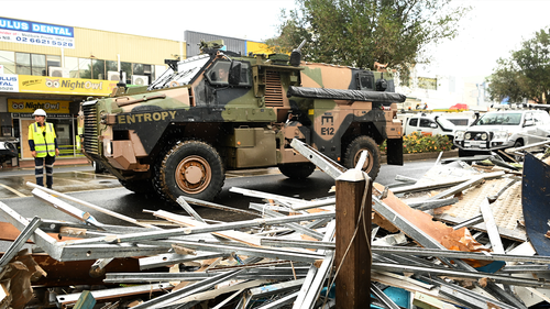 Un véhicule de l'armée passe devant des débris dans le centre-ville touché par les inondations le 29 mars 2022 à Lismore, en Australie.  Des ordres d'évacuation ont été émis pour les villes de la région des rivières du Nord de la Nouvelle-Galles du Sud, avec des inondations soudaines attendues.