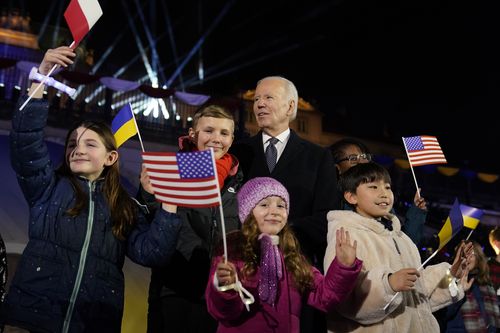 President Joe Biden stands with children after delivering a speech marking the one-year anniversary of the Russian invasion of Ukraine, Tuesday, Feb. 21, 2023, at the Royal Castle Gardens in Warsaw